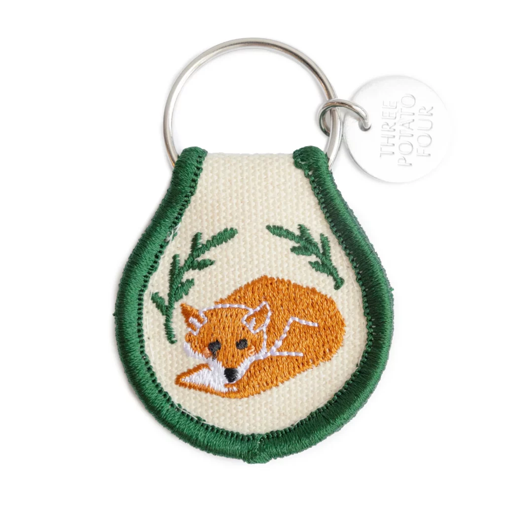Vue du porte-clés “Fox” : patch brodé en coton naturel avec motif renard, broderie double-face, anneau métal, dimensions compactes.