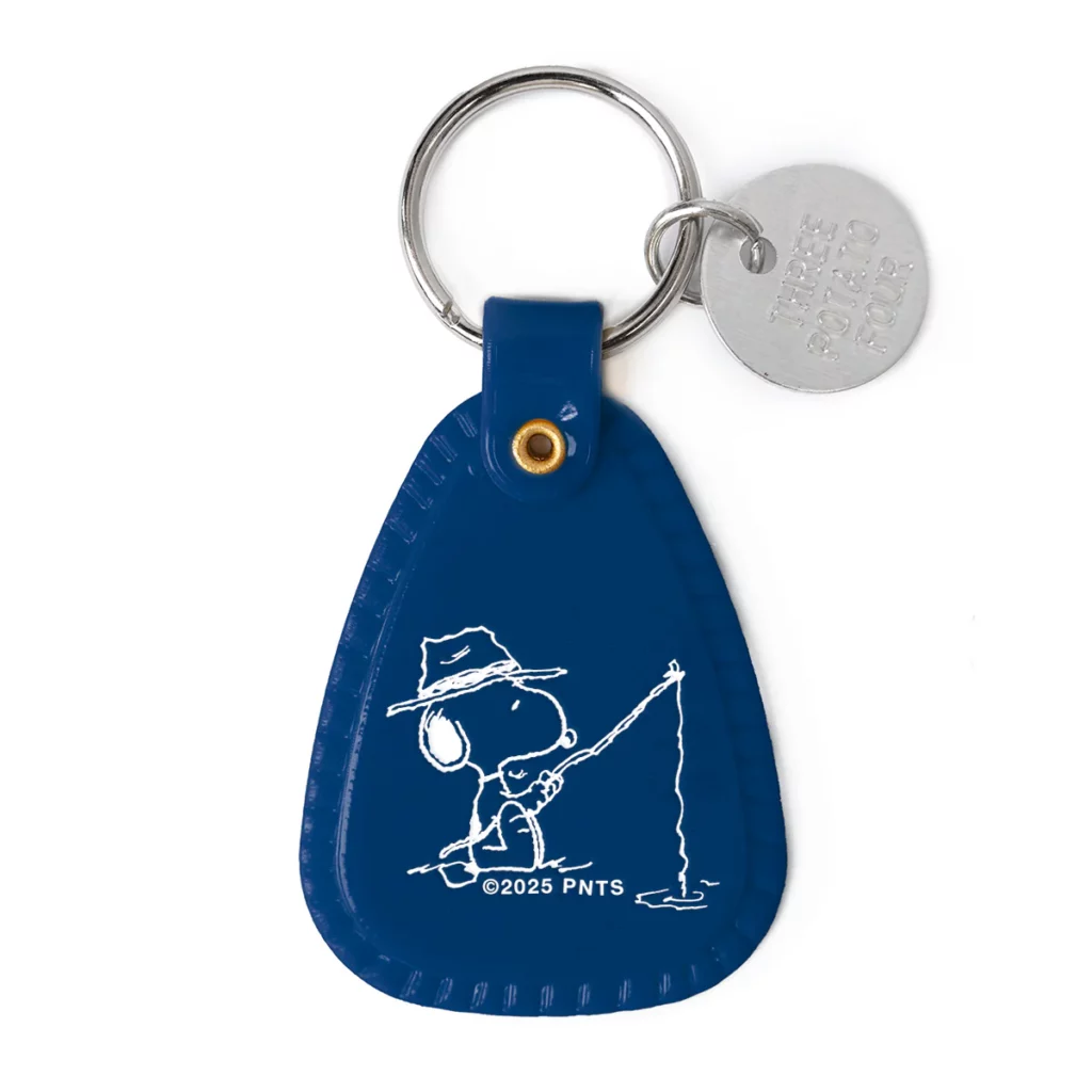 Vue du porte-clés “Snoopy Fisherman” : plastique semi-souple, illustration vintage de Snoopy en pêche, anneau métal, format compact, prêt à être accroché à vos clés ou sac.