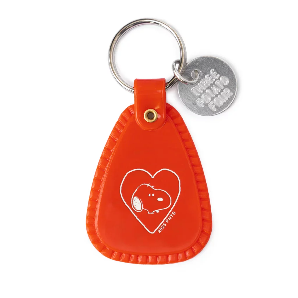 Vue du porte-clés “Snoopy Heart” : plastique souple, impression d’époque motel / road-trip, badge décoratif rouge / blanc, format compact 1.5″ × 2.25″, anneau métal part of key ring.